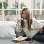 cheerful young woman eating sushi at home