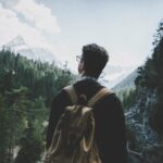 man standing on rocky mountain under white cloudy sky